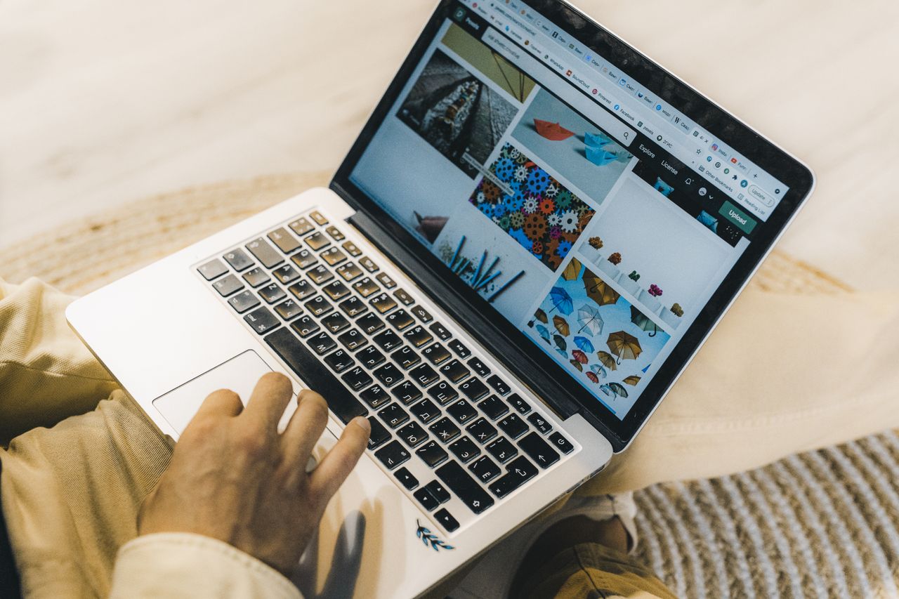 why-choose-us A person using a laptop to browse stock photo websites. Freelancing work in a cozy setting.